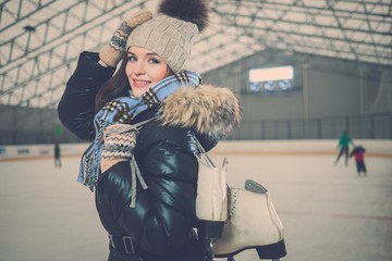 Wall Mural - Cheerful girl with skates on ice skating rink