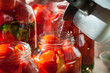 Canning process of tomato in mason jar. On background is few