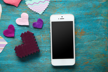 Wall Mural - Smart phone with blank screen and hearts on old wooden table