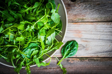 Wall Mural - Fresh arugula and spinach salad on rustic background