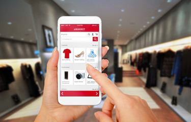 Poster - Smart phone online shopping in woman hand. Shopping center in background. Buy clothes shoes accessories with e commerce web site