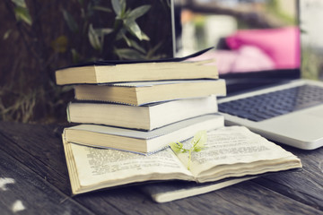 Poster - Pack of books with laptop on the wooden table outdoor