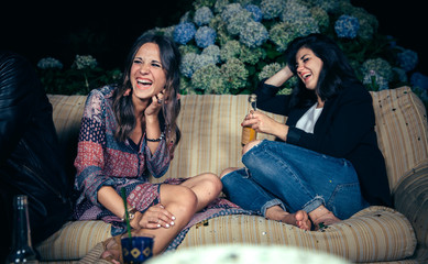 Happy women friends laughing and drinking in a party