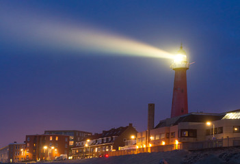 Lighthouse shines a beam of bright light into the night in Scheveningen, Netherlands