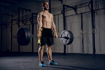 Wall Mural - Young athlete lifting barbells at gym