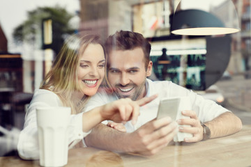 Wall Mural - Couple using smartphone in coffee shop