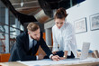 © baranq - Busy architects at office working on construction plan