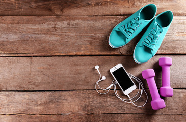 Sticker - White cellphone with headphones and pink dumb bells and gumshoes on wooden background