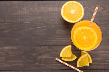 Fresh orange juice and oranges on wooden background