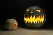 Two halloween pumpkins funny and spooky on wood table with dark on background
