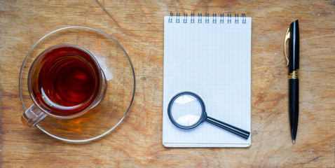 Small notebook with a Cup of tea, stick on a rustic wood backgro