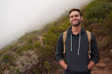 Wall Mural - Young hiker smiling while standing on a misty mountain side