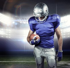 Poster - American football player looking down while holding ball