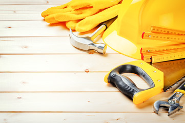 Hard hat and various tools on wooden background