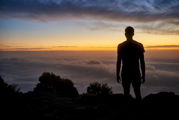 Wall Mural - Silhouette of a man on a mountain with a  cloudy sunrise