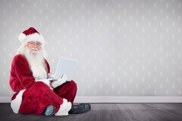 Poster - Composite image of santa sits and uses a laptop