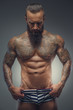 © Fxquadro - Tattooed muscular man with beard in stripes panties.