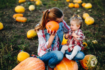 mother and daughter sitting on pumpkins
