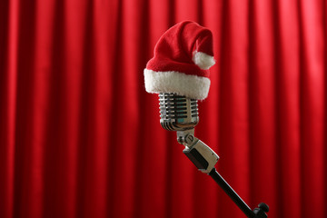 Wall Mural - Vintage microphone with Christmas hat on red curtain background