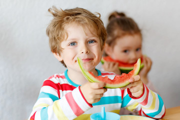 Little kid boy and girl eating healthy food watermelon