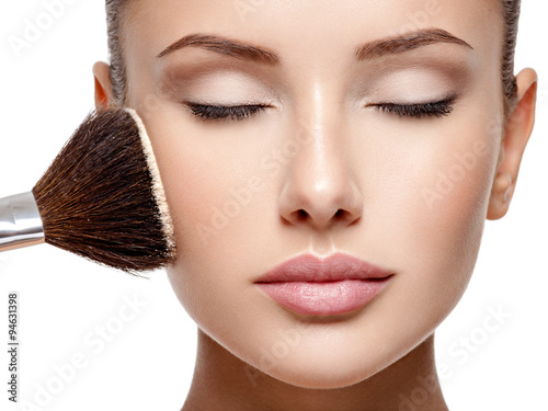 Poster woman applying dry cosmetic tonal foundation on the face