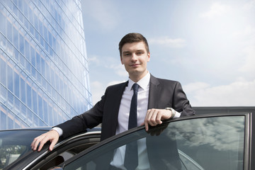 Young businessman standing near his car