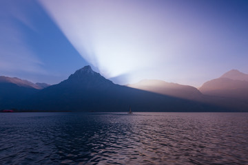 Canvas Print - Grandiose game of light and shadow. Sun set behind the mountain peaks.