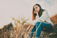 Teenage Girl Sitting Alone On Autumn Cold Day. Lonely Sad Young Woman Wearing Warm Sweater Thinking And Hesitating. Loneliness And Solitude Concept.