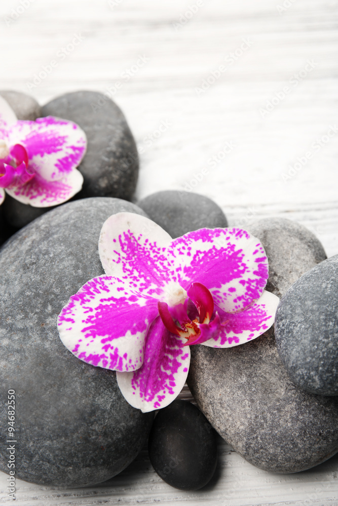 Spa stones and orchids on wooden background