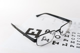 Fototapeta Miasta - Eye glasses on eyesight test chart background close up