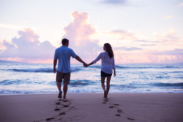 lovers walking on the beach at sunset on vacation