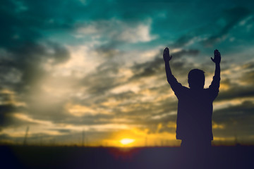 Wall Mural - Silhouette of man with raised hands over blur cross concept for