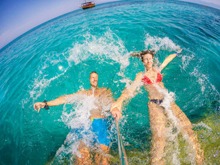 Couple in love refreshing on vacation. Jumping at sea. Wide angle selfie shot.