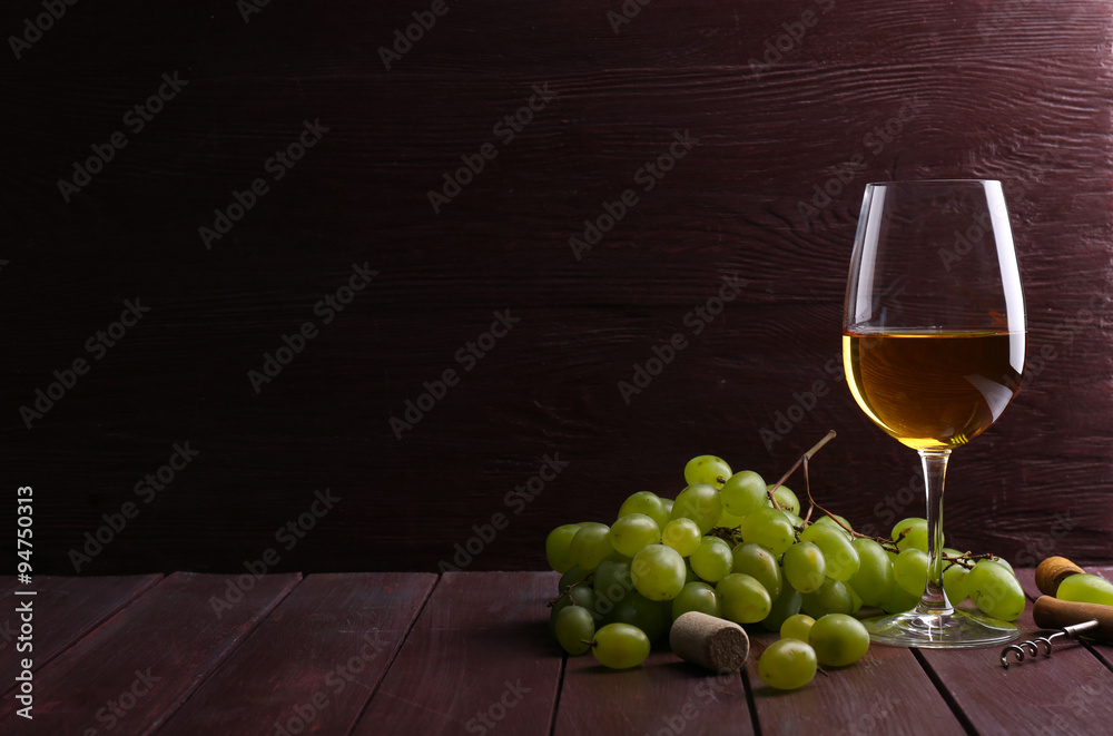 Glass of wine with grape on wooden background