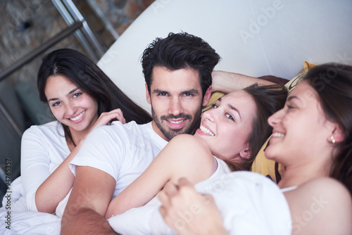 Foto handsome man in bed with three beautiful woman