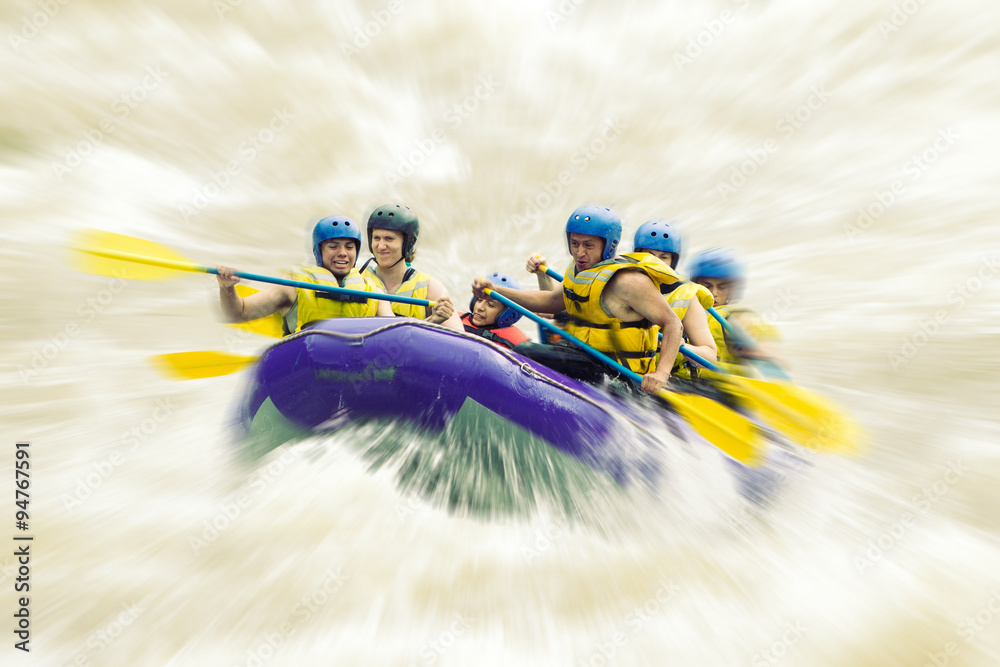 A team of adventurers race down white water rapids on a raft ...