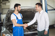 © luckybusiness - Smiling client and mechanic shaking hands