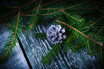 Christmas card. Cone with fir tree twigs on rustic wooden backgr