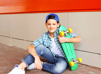 Portrait of stylish teenager boy with skateboard in city