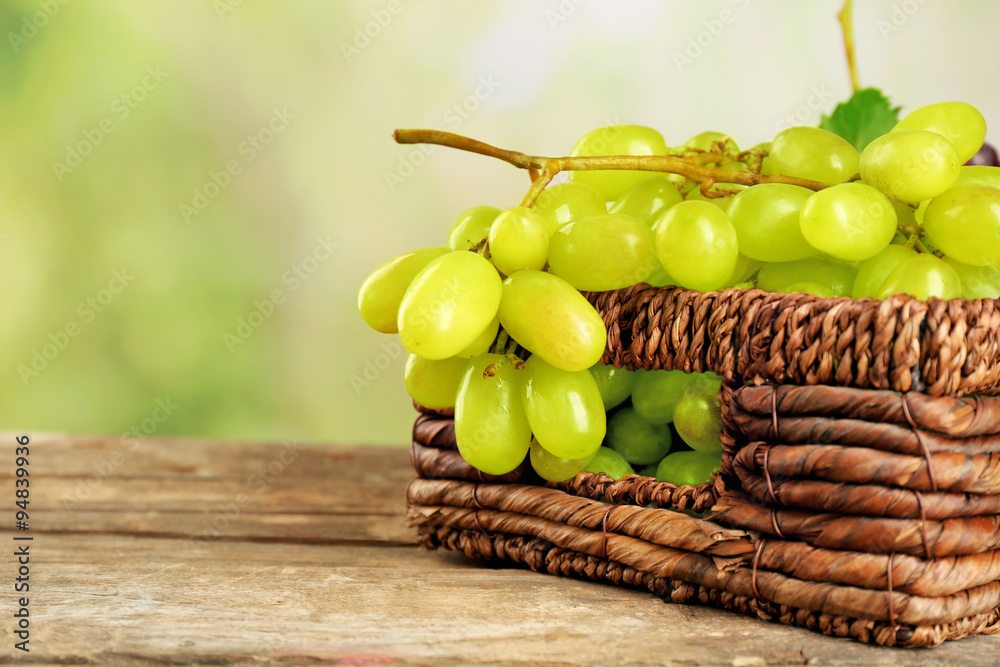 Bunch of white grape in basket  on wooden table