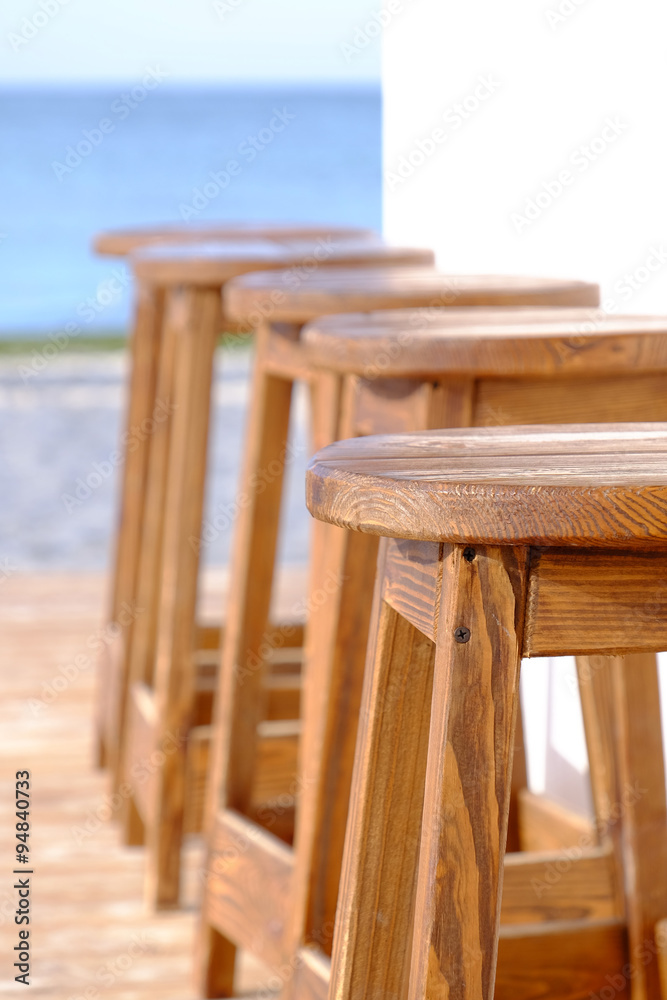 Beach bar wooden stools in a row, close up