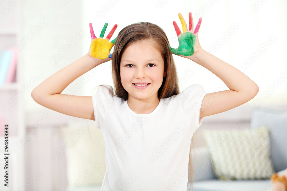 Little girl with hands in paint, on home interior background
