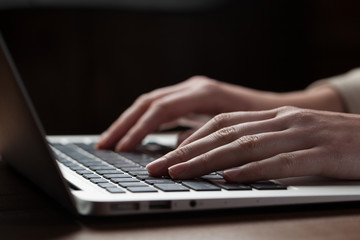 Wall Mural - woman hands using laptop at office desk, with copyspace in dark