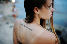 Girl With A Tattoo On His Back Against The Sea