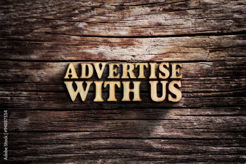 Fotografía Advertise with us. Words on old wooden board.