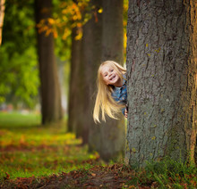 Little Girl Hugging A Tree And Smile In Park