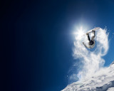 Snowboarder making high jump in clear blue sky. Concept: fun, sport, courage, adventure, danger, extreme. Large copy space on the left side.