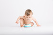 © revelpix - a cute 1 year old sits in a white studio setting. The boy in the middle of the shot about to get another face full of cake. He is only dressed in a white diaper