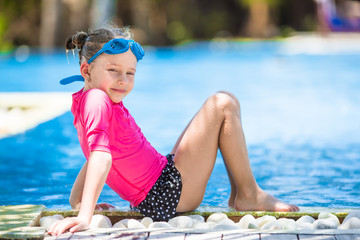 Adorable little girls at mask and goggles in outdoor swimming pool