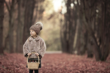 Wall Mural - Adorable little girl with a basket outdoors at beautiful autumn park